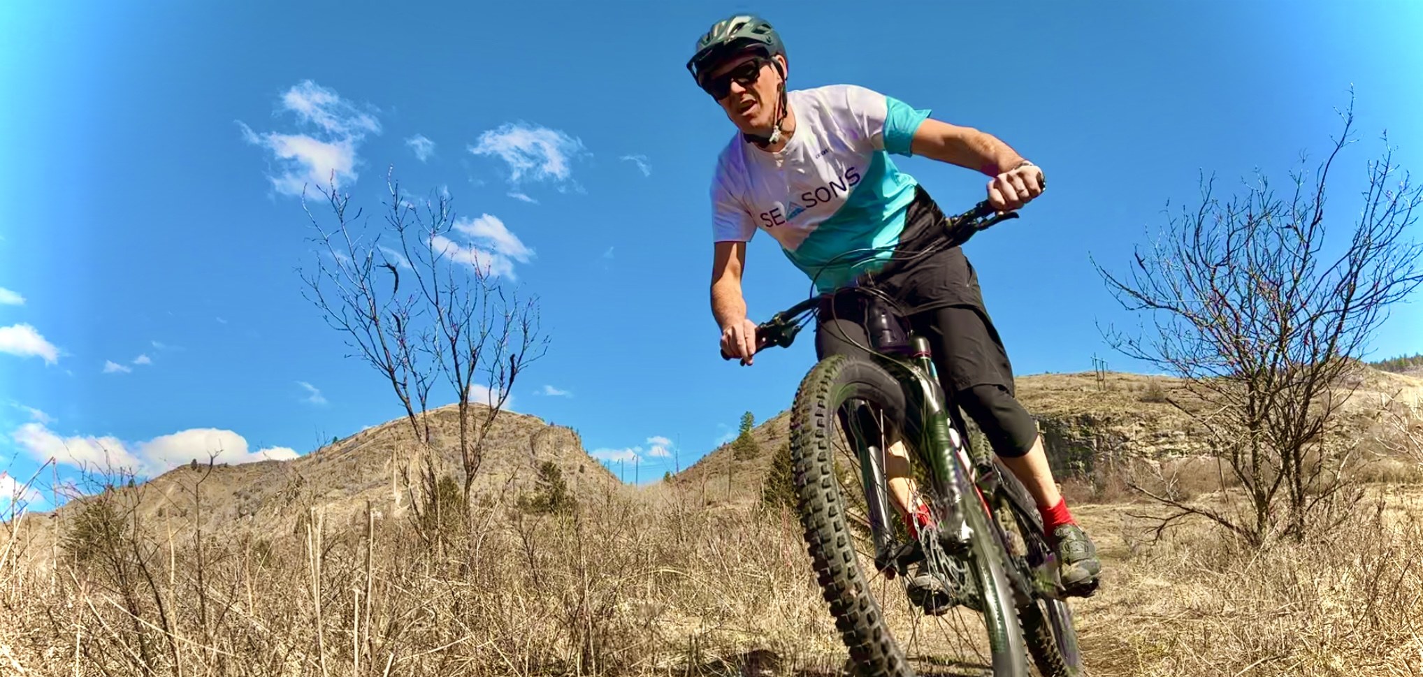 Mountain biker riding toward the camera on a dry hillside trail